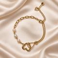 Golden Heart & Pearl-Style Bracelet with open heart, three pale beads and asymmetric gold-tone chains on satin