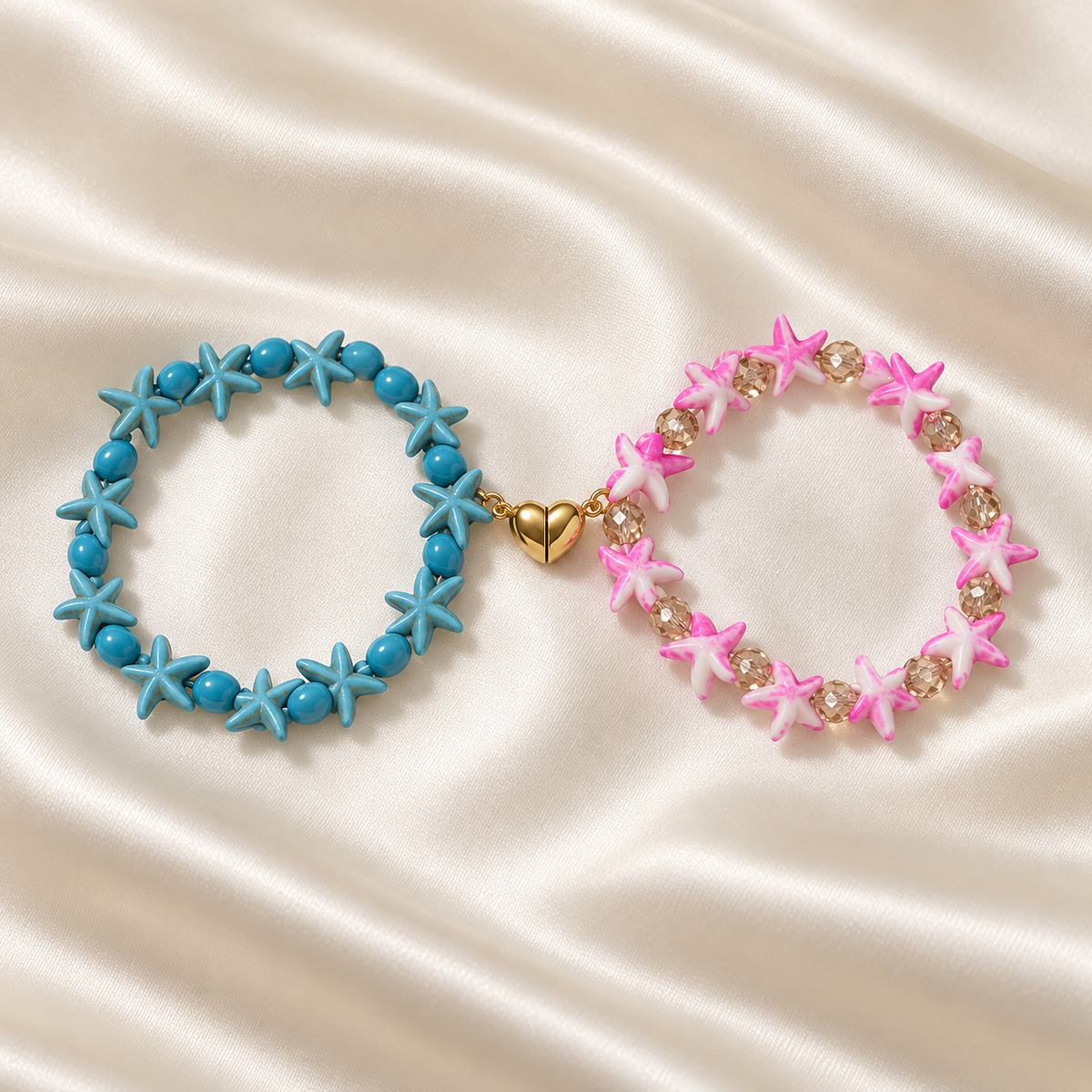 Starfish Friendship Bracelet Pair on pale champagne satin: turquoise-blue starfish bracelet and pink-and-white starfish bracelet connected by a gold-tone split heart.