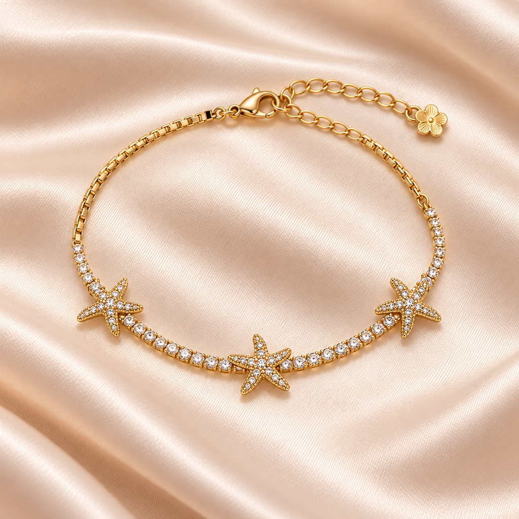 Starfish Sparkle Bracelet on pale champagne satin, showing three starfish motifs, gold-tone chain, clasp and extender.