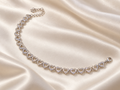 Silver-tone open heart link bracelet with clear sparkle on ivory satin
