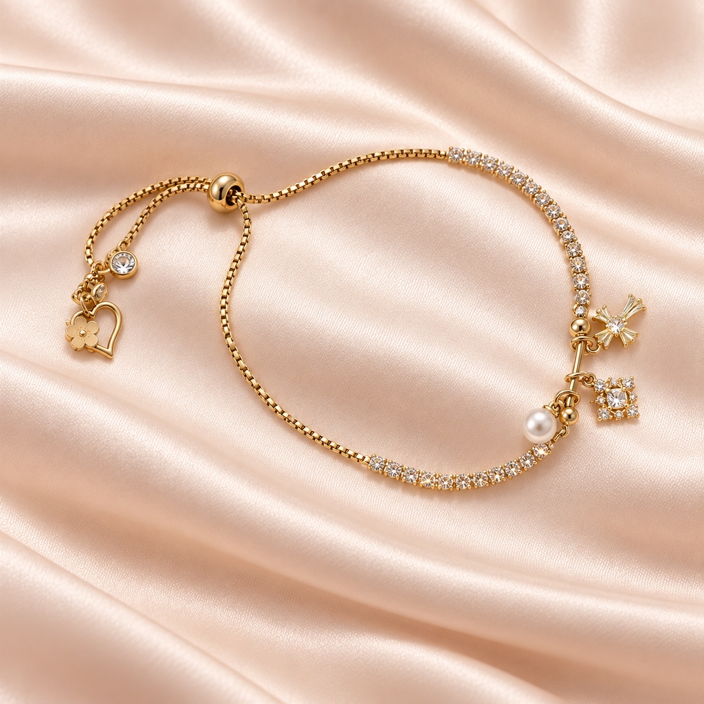 Golden Sparkle Charm Slider Bracelet on champagne satin, showing clear sparkling sections, a pearl-style bead, tiny charms and the adjustable slider.