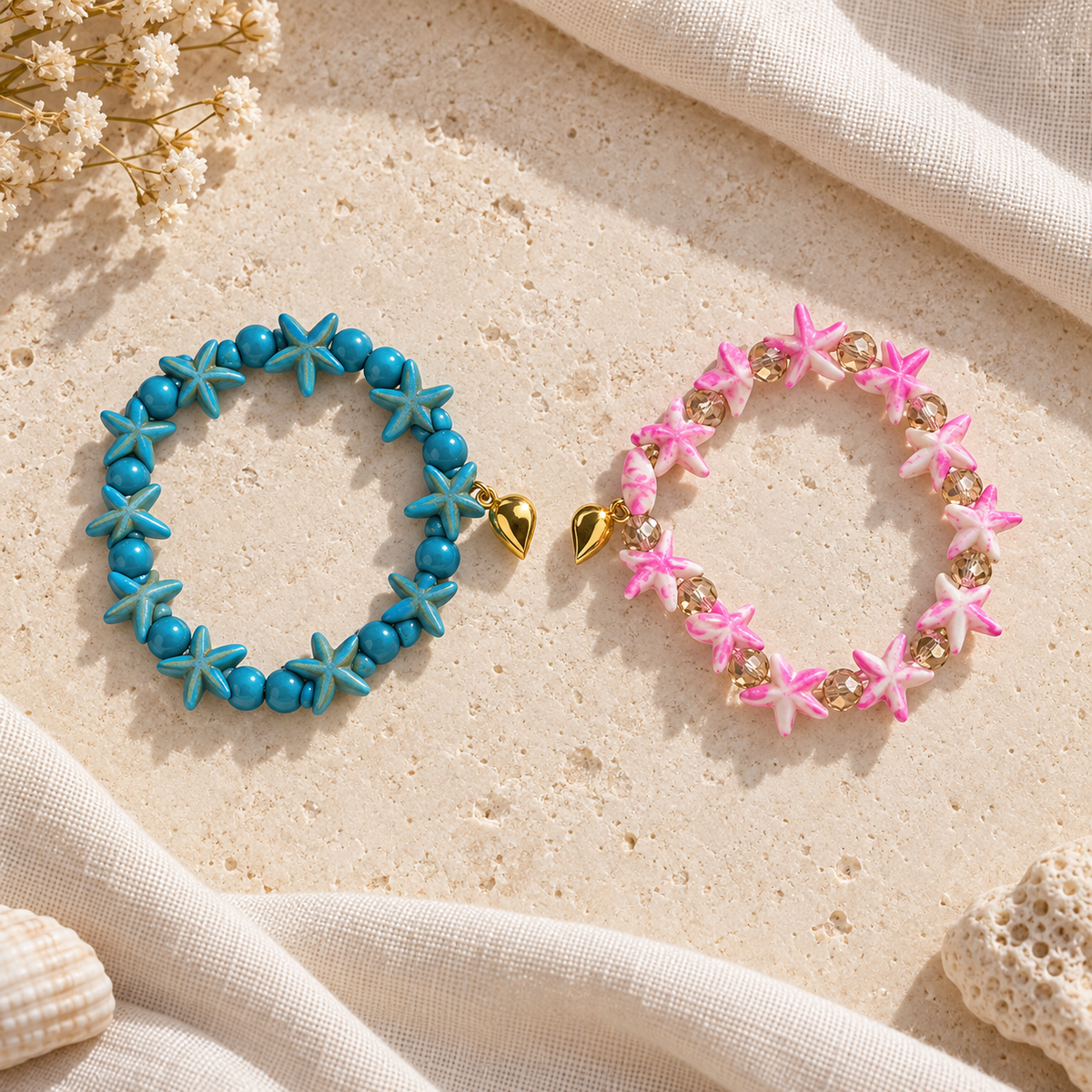 Two separate Starfish Friendship Bracelets on ivory stone and linen, one blue and one pink, each with a half of the gold-tone heart.