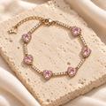 Blush Heart Sparkle Bracelet styled on ivory stone and linen, showing its six pink heart settings and clear sparkle links.