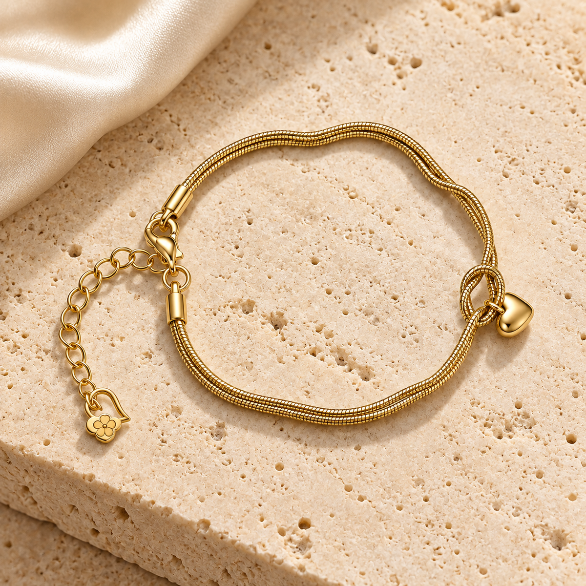 Golden Heart Knot Bracelet styled on beige stone with its double gold-tone chains, central knot, and small heart charm visible.
