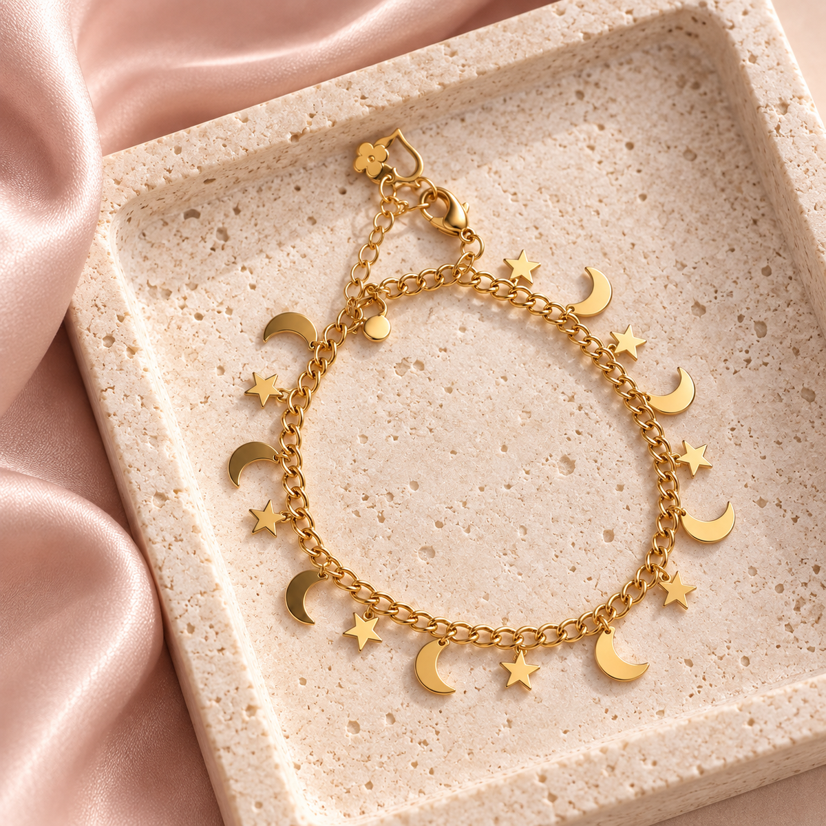 Golden Moon & Stars gold-tone bracelet styled on a pale stone tray with alternating dangling moon and star charms