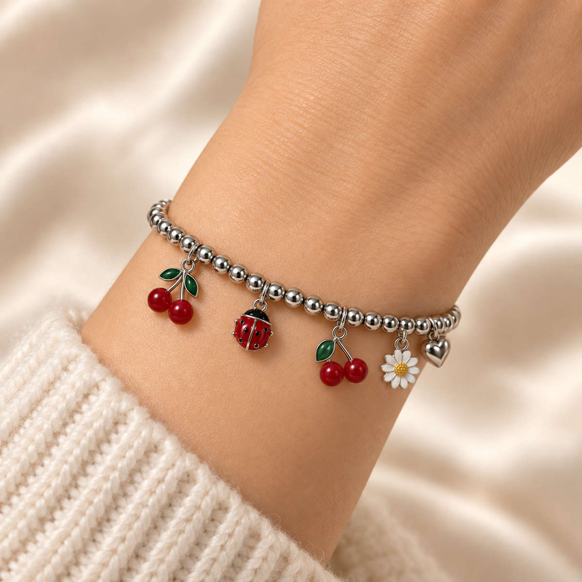 Close-up of the Silver Cherry & Ladybug Charm Bracelet worn snugly around a wrist, showing bright silver beads, cherry pairs, a red ladybug and daisy.
