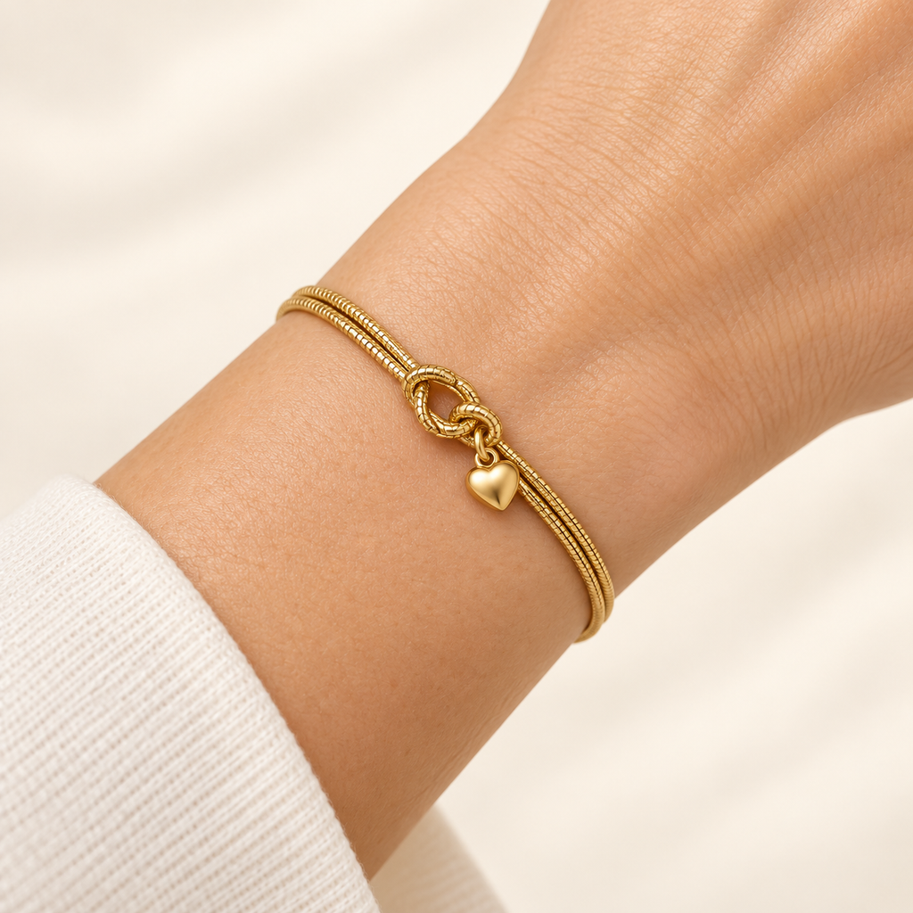 Close-up of the Golden Heart Knot Bracelet fastened snugly around a wrist, showing the double chains and small heart charm.