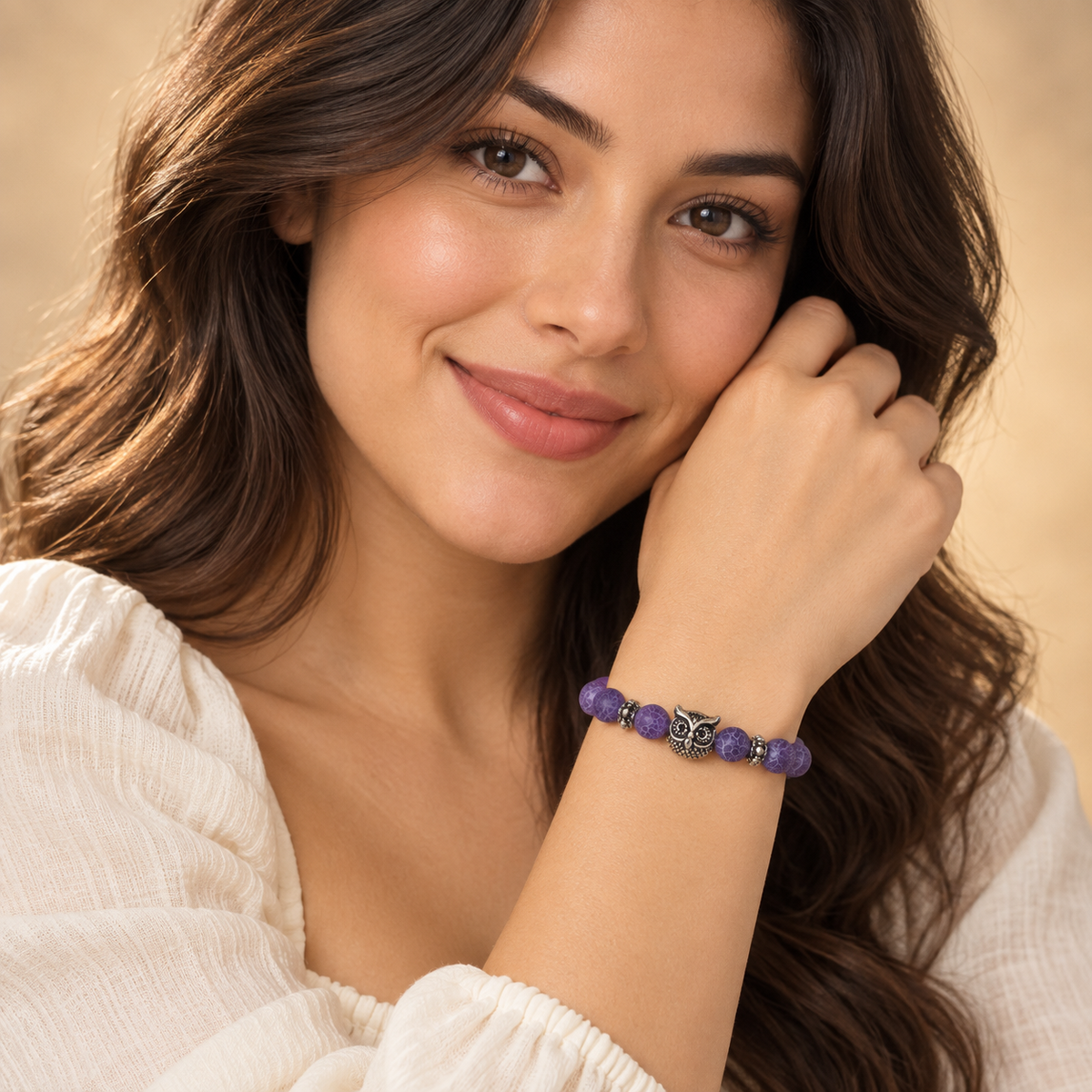 Full-face model portrait wearing the Purple Owl Bead Bracelet snugly around a raised wrist, with the silver-tone owl visible.