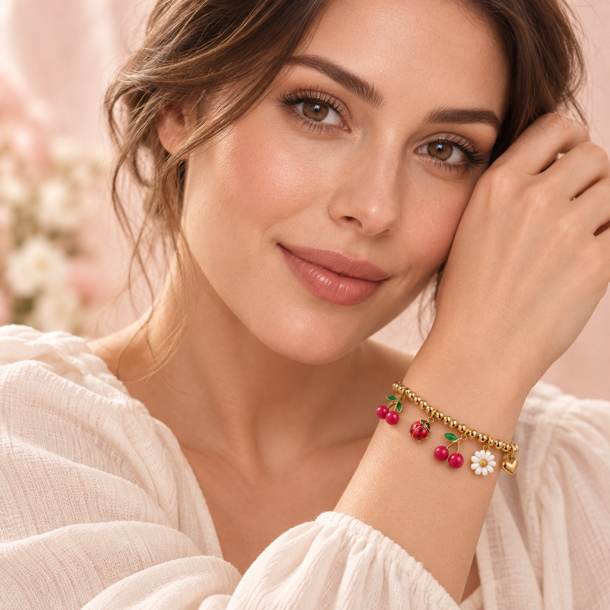 Model showing her face and the gold-tone Cherry Garden charm bracelet with cherries, ladybug, daisy, and heart worn snugly on her wrist