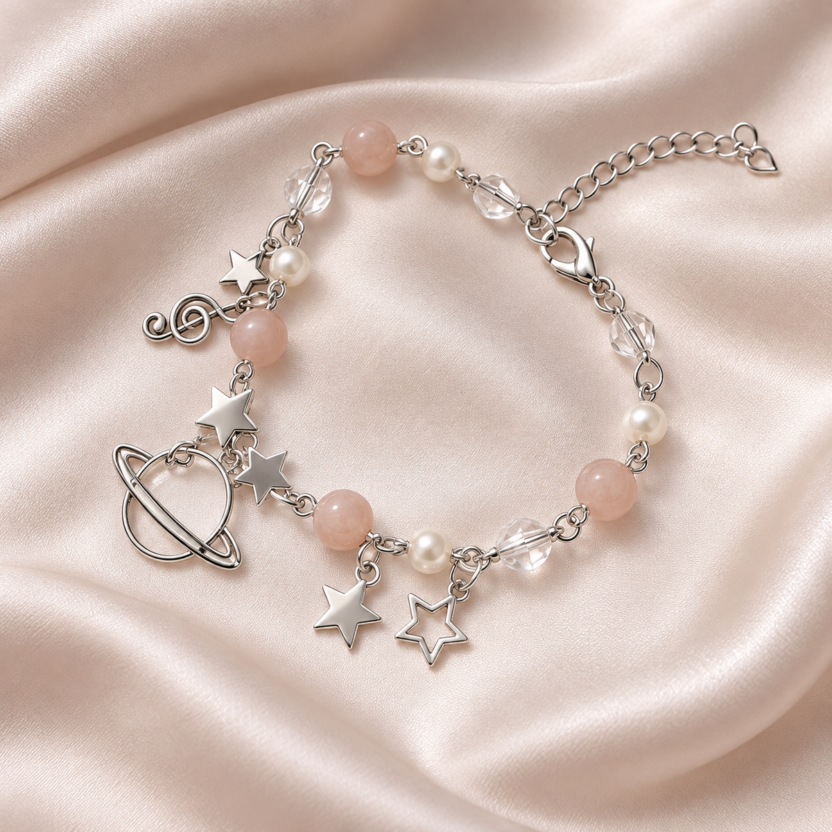 Celestial Orbit Charm Bracelet with silver-tone ringed planet and star charms, blush and pearl-like beads, on ivory satin.