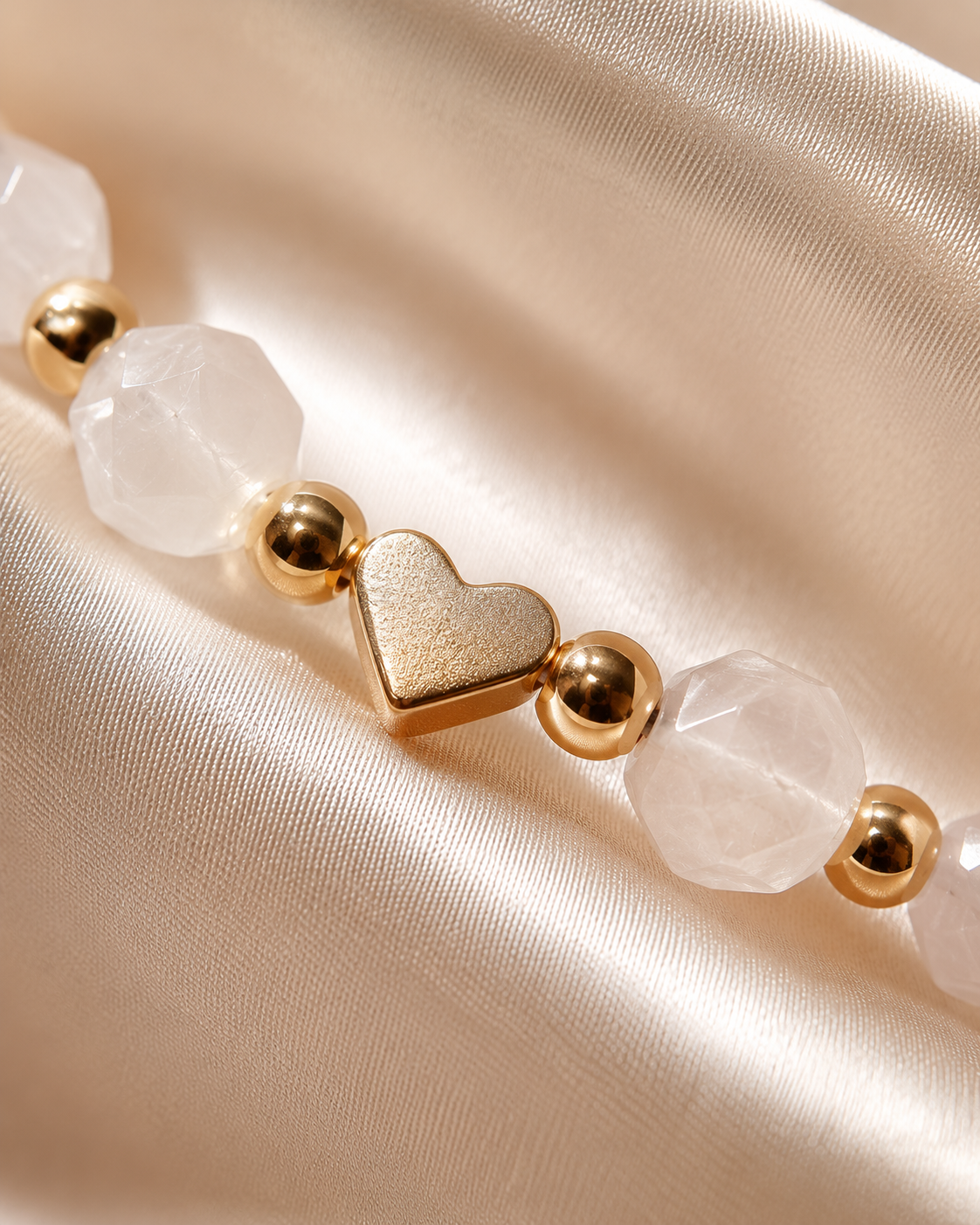 Close-up of gold heart centerpiece with blush-white faceted beads and polished gold spacer beads.