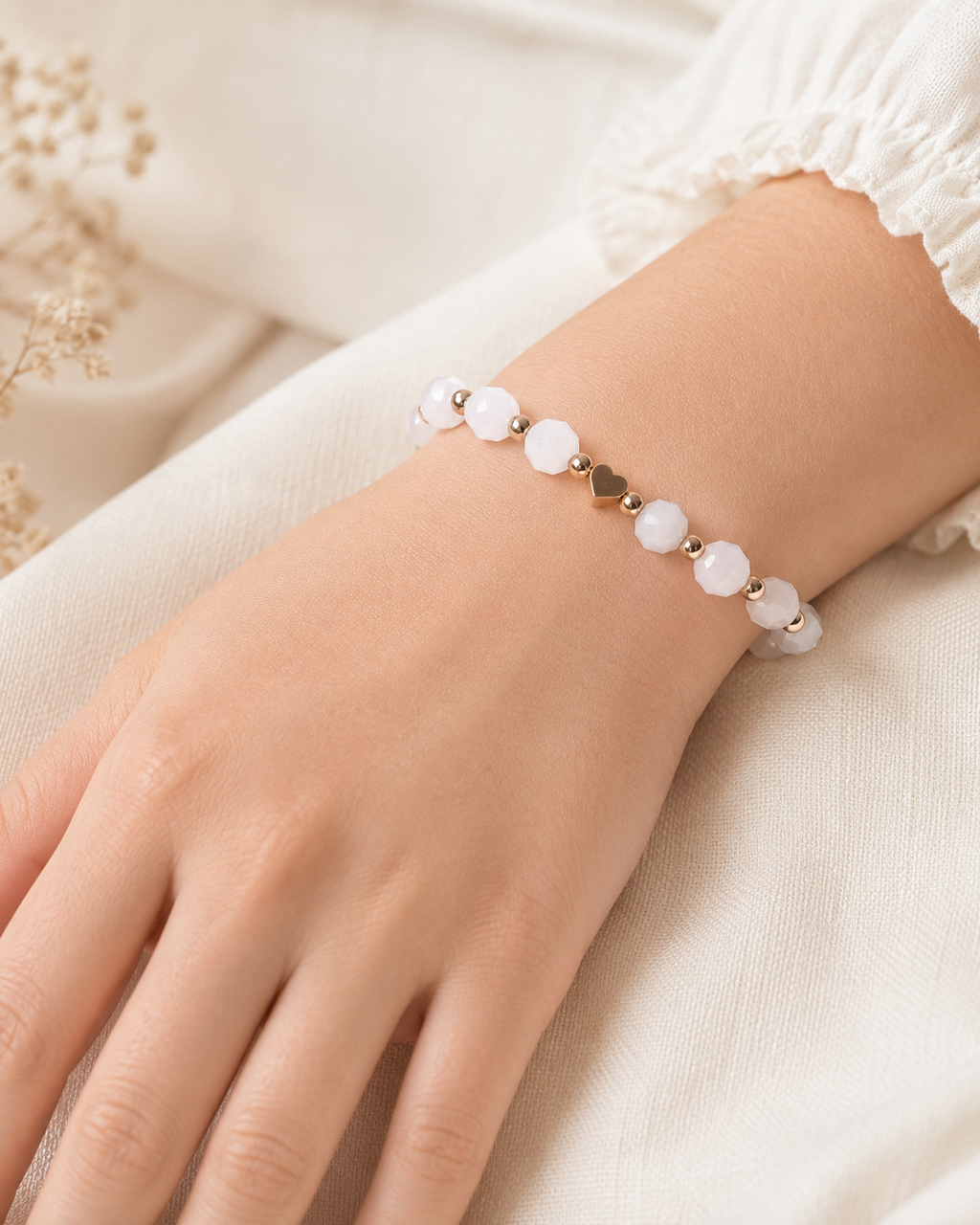 Blush Heart Bracelet with soft white faceted beads and gold heart charm worn on wrist.