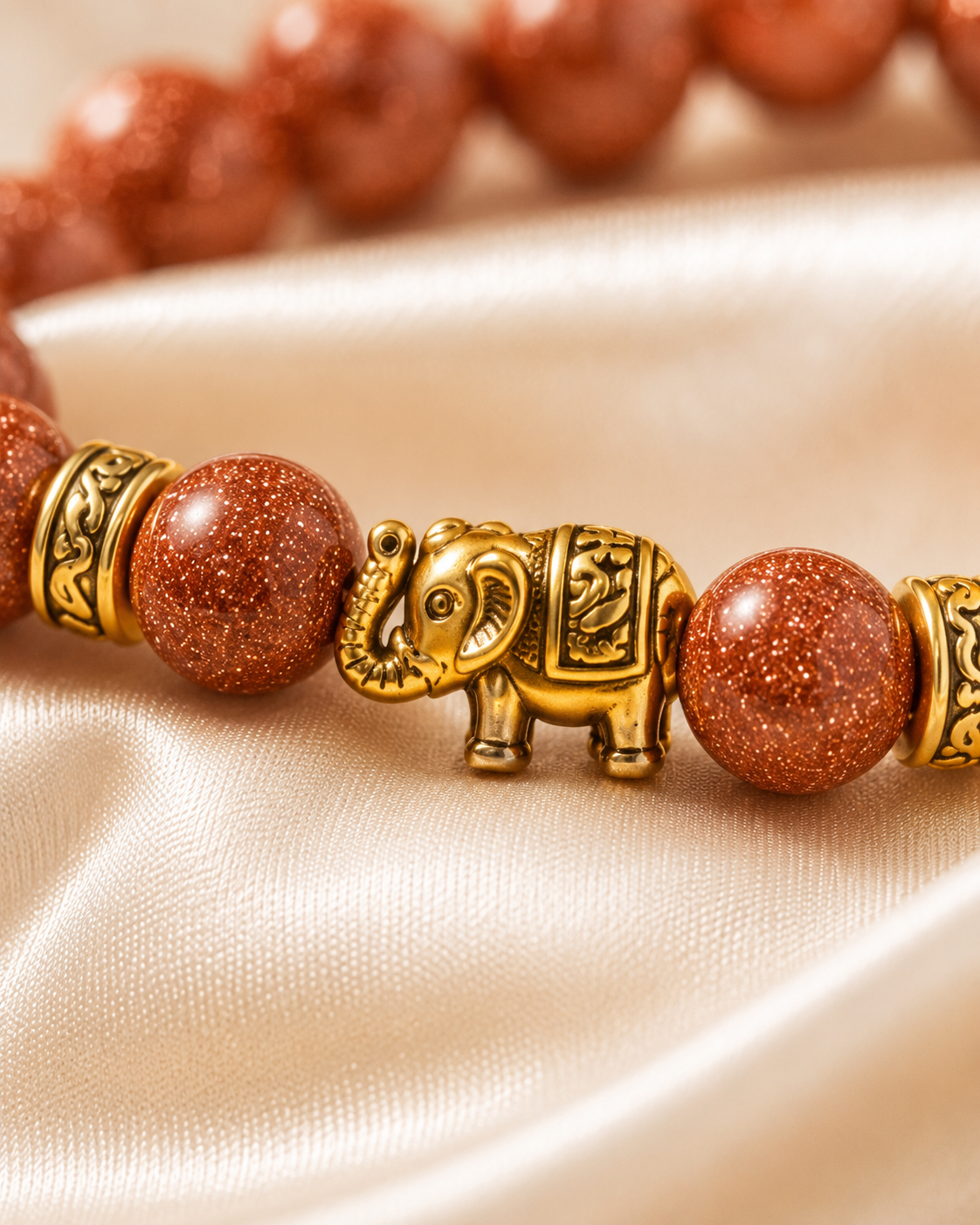 Close-up of gold elephant centerpiece with sparkling copper-brown beads and decorative gold spacer beads.

