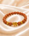 Golden Elephant Bracelet with sparkling copper-brown beads, gold spacer accents, and gold elephant centerpiece on satin fabric.