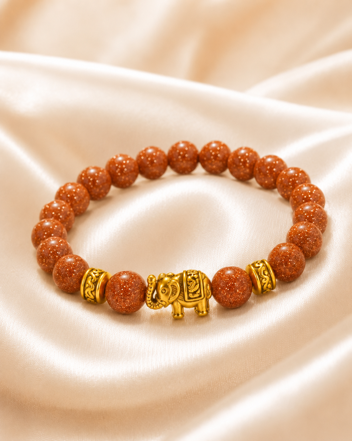 Golden Elephant Bracelet with sparkling copper-brown beads, gold spacer accents, and gold elephant centerpiece on satin fabric.