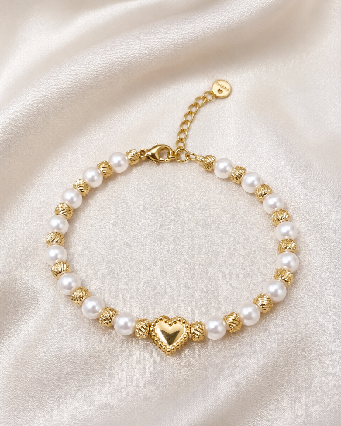 Golden Pearl Heart Bracelet with white pearl-style beads, detailed gold swirl spacer beads, and gold heart centerpiece on satin fabric.