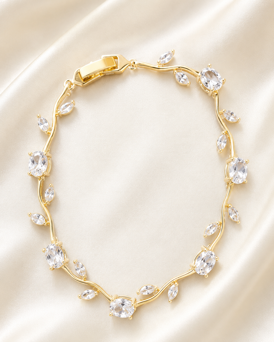 Golden Vine Bracelet with gold-tone vine design and clear crystal stones displayed on soft satin fabric.