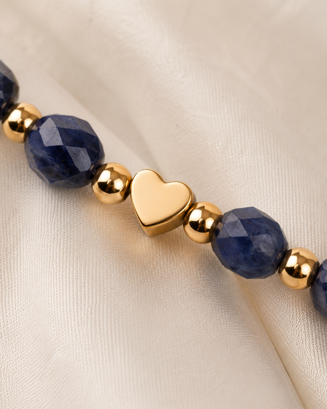 Close-up of gold heart centerpiece with navy-blue faceted beads and polished gold spacer beads.