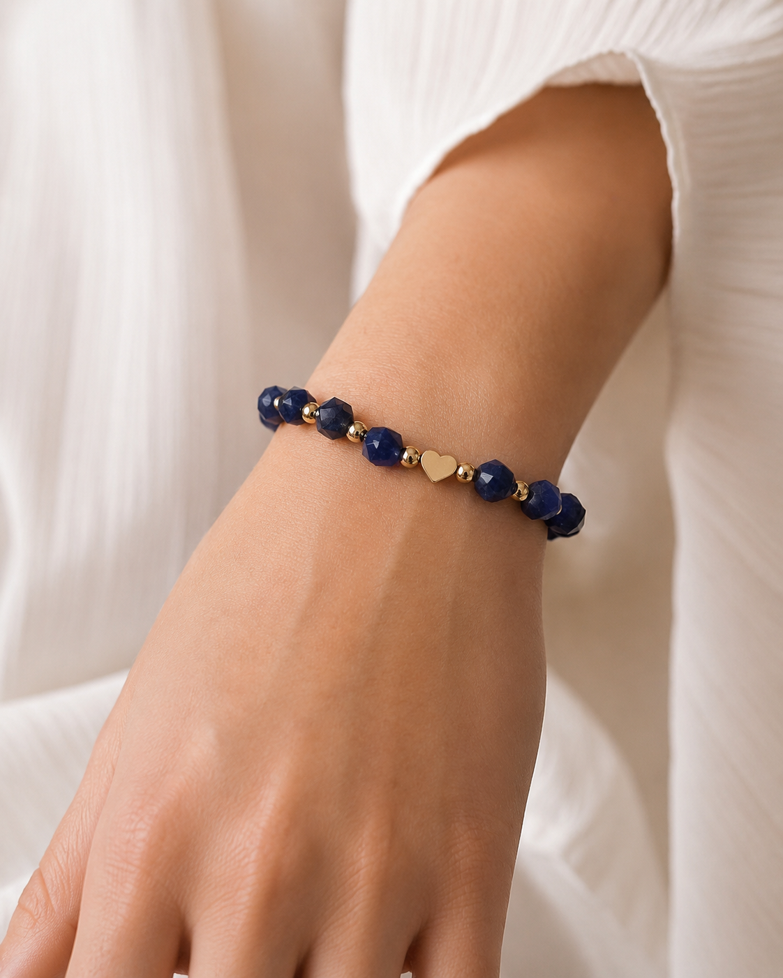 Midnight Heart Bracelet with deep blue faceted beads and gold heart centerpiece worn on wrist.

