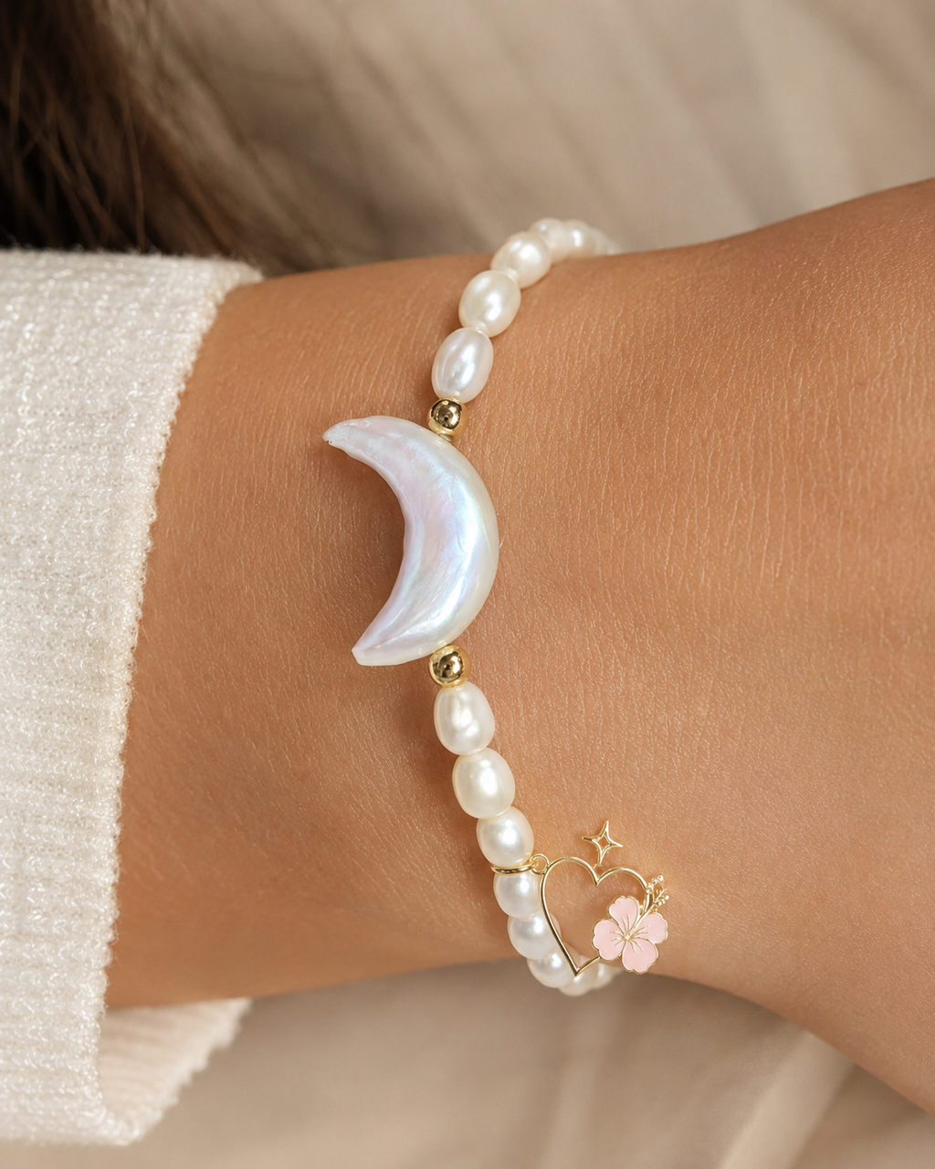 Ohana Collection freshwater pearl bracelet with crescent moon centerpiece and signature charm worn on hand.