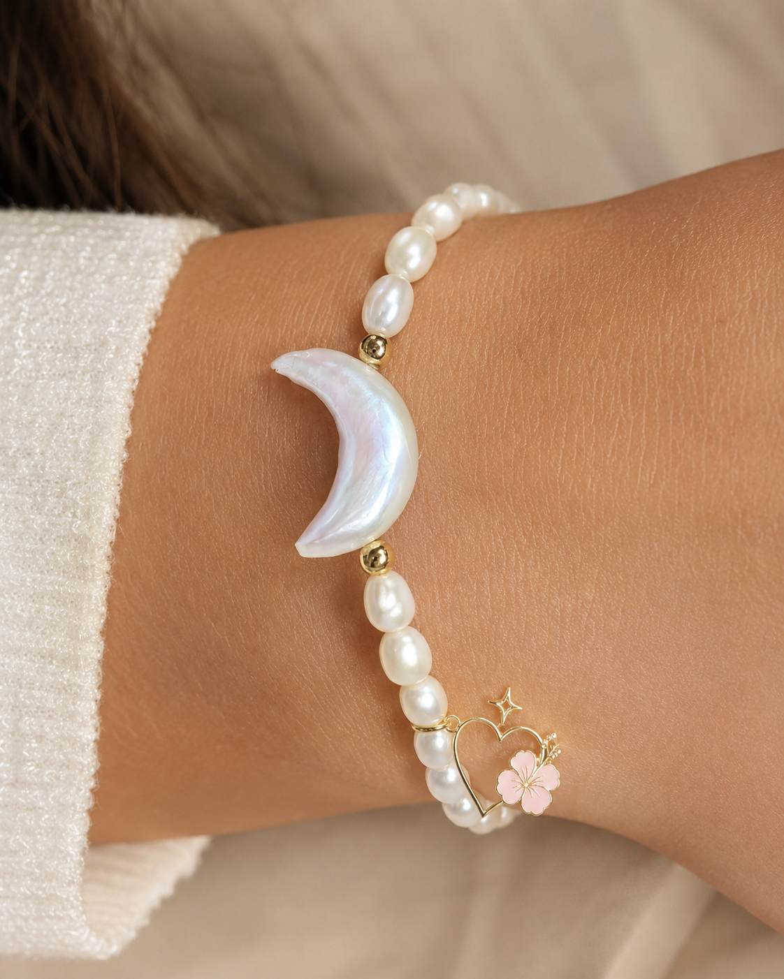 Ohana Collection freshwater pearl bracelet with crescent moon centerpiece and signature charm worn on hand.