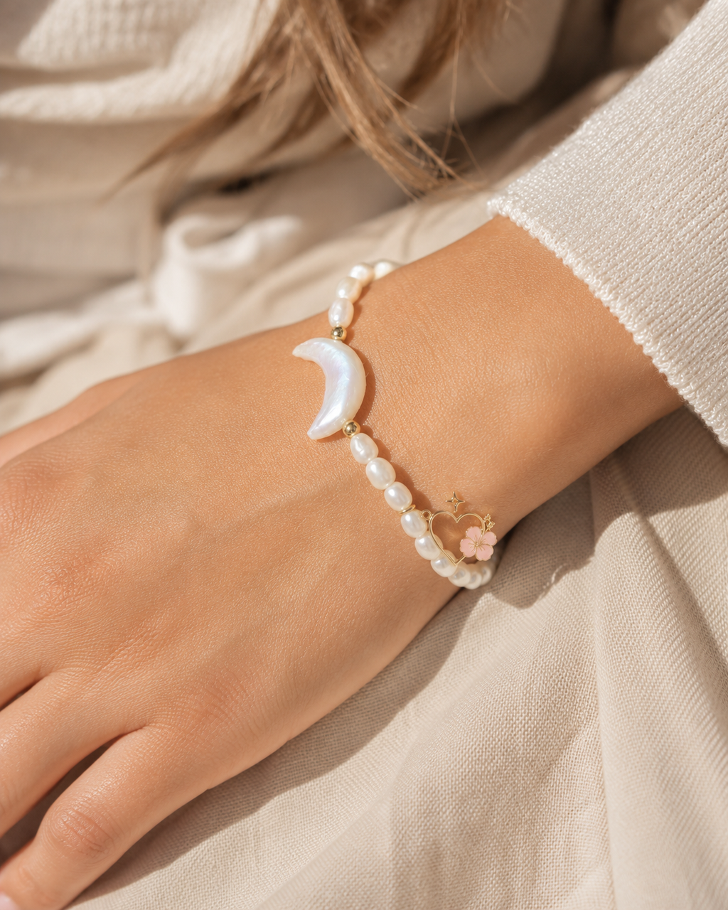Freshwater pearl moon bracelet with gold accents and signature Ohana heart hibiscus charm on wrist.
