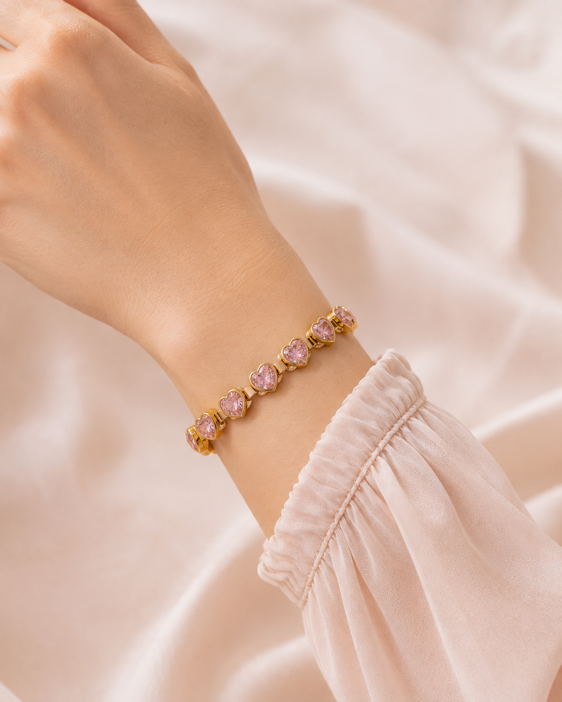 Close-up of the Pink Heartstone Bracelet featuring sparkling pink heart-shaped stones in a polished gold setting worn on the wrist.