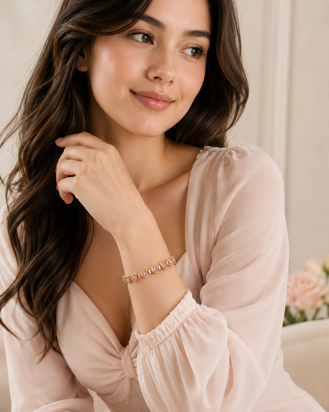 Model wearing the Pink Heartstone Bracelet with pink heart-shaped gemstones and polished gold links styled with a soft blush outfit.