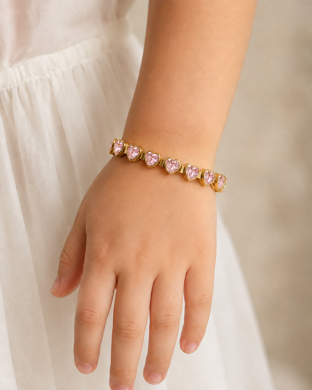 Pink Heartstone Bracelet with gold links and pink heart-shaped stones worn on wrist.

