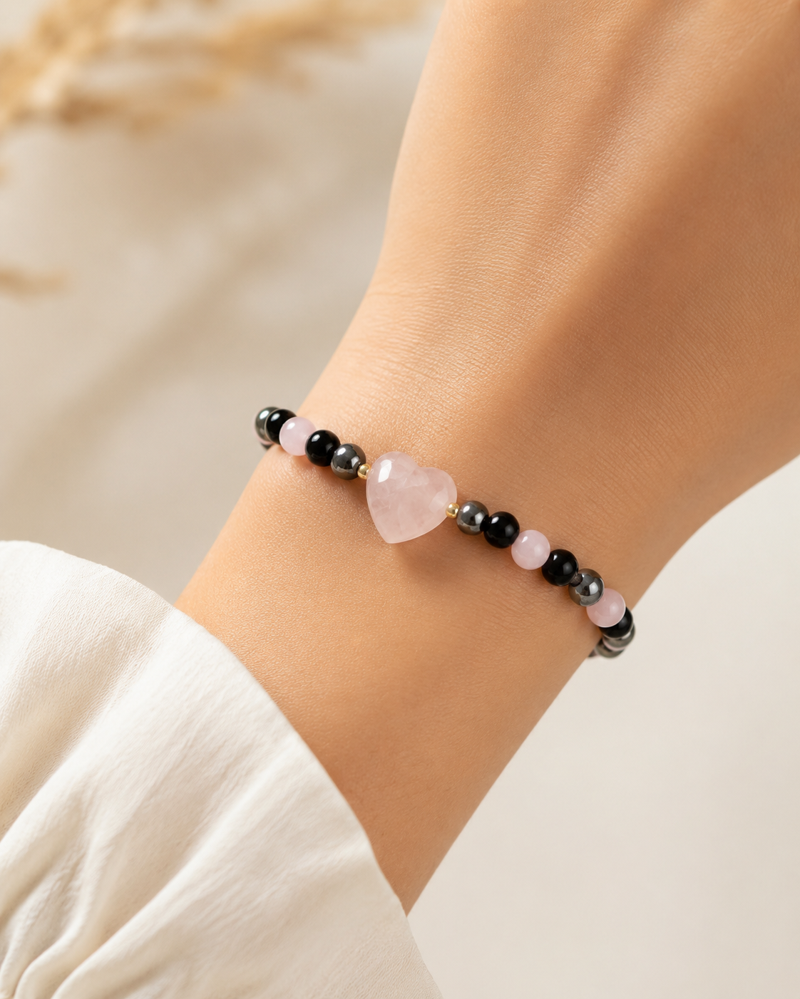 Rose Shadow Heart Bracelet with pink heart centerpiece and black, gray, and pink beads worn on wrist.

