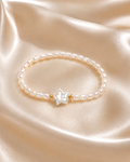 Starlight Pearl Bracelet with round pearl beads, iridescent star centerpiece, and small gold accent beads on satin fabric.